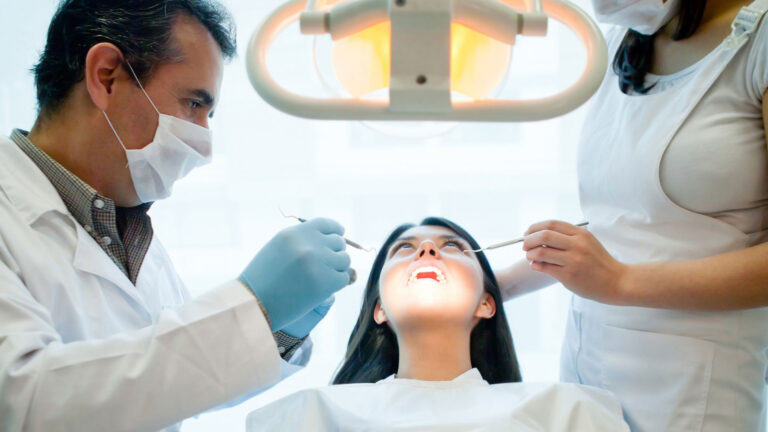 Team of dentists performing a dental evaluation on a young woman